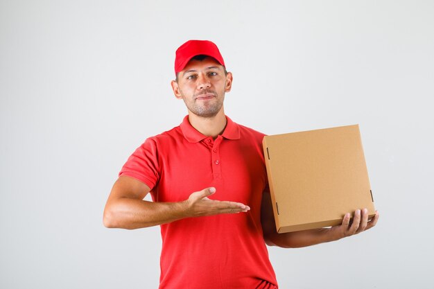 赤い制服を着た彼の手でピザの箱を示す配達人