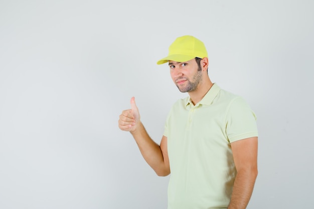 Delivery man showing thumb up in yellow uniform and looking sensible , front view.