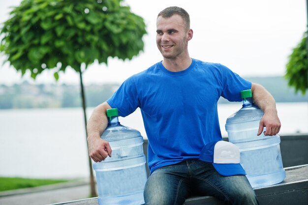 Delivery man sitting with water bottles outdoor