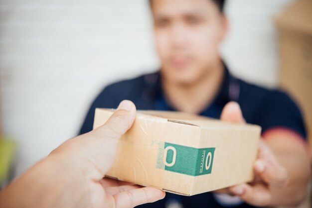 delivery man smiling and holding a cardboard box