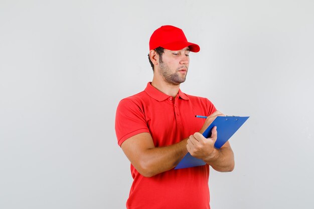 Delivery man taking notes on clipboard in red t-shirt