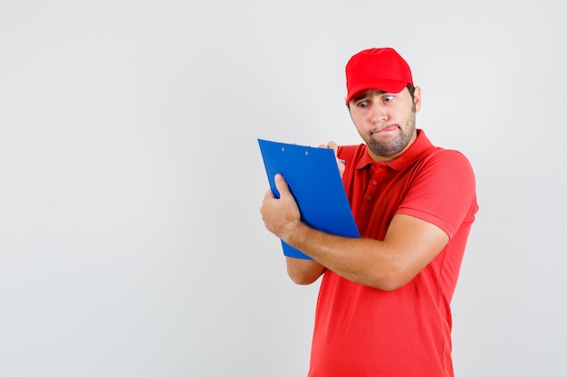 Delivery man taking notes on clipboard in red t-shirt