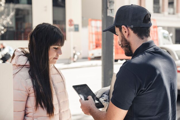 Человек доставки с помощью цифрового планшета рядом с женщиной-клиентом
