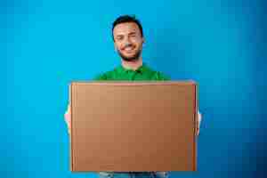 Free photo delivery man with box in studio against blue background