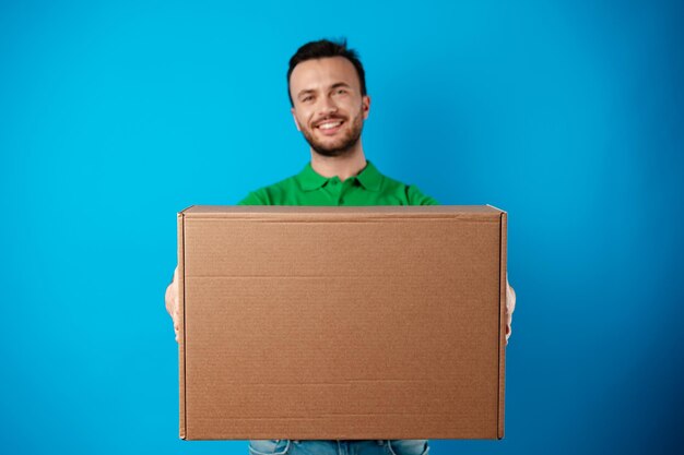 Delivery man with box in studio against blue background