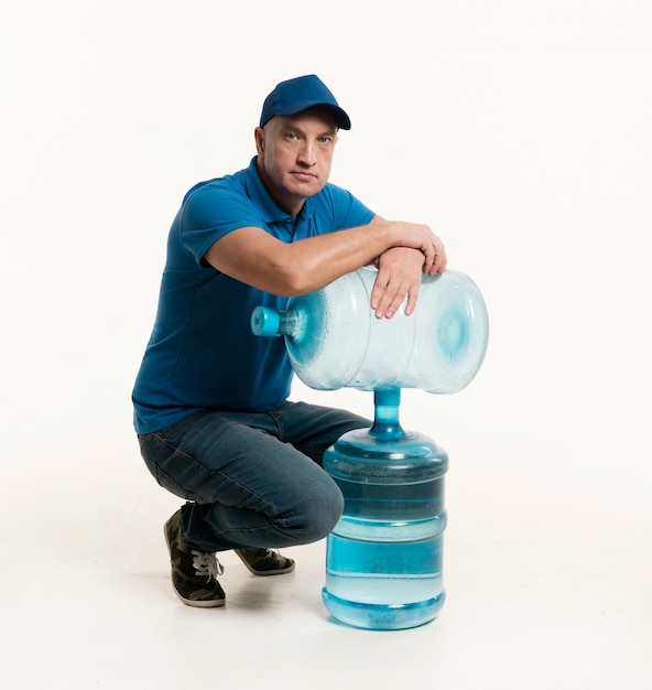 Доставка человек с крышкой позирует с бутылками с водой