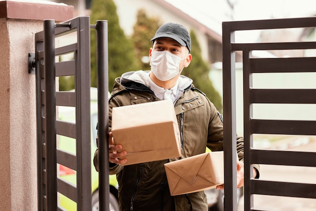 Free photo delivery man with package wearing mask