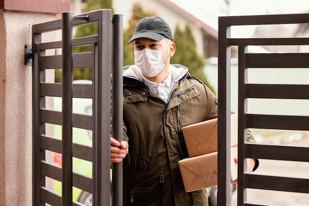 Free photo delivery man with package wearing mask