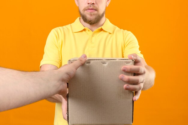 오렌지에 고객에게 상자 패키지를주는 노란색 폴로 셔츠와 모자 배달 남자