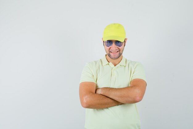 Delivery man in yellow uniform standing with crossed arms and looking confident , front view.