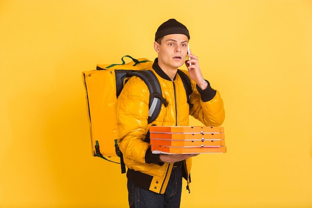 delivery service concept. man delivers food and shopping bags isolated on yellow wall