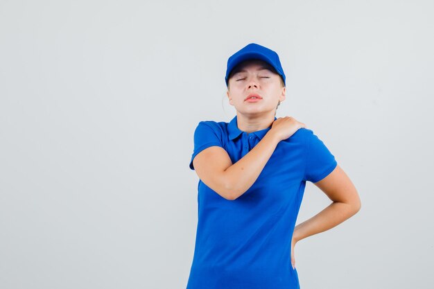 어깨 통증으로 고통 받고 피곤해 보이는 파란색 티셔츠와 모자에 배달 여자