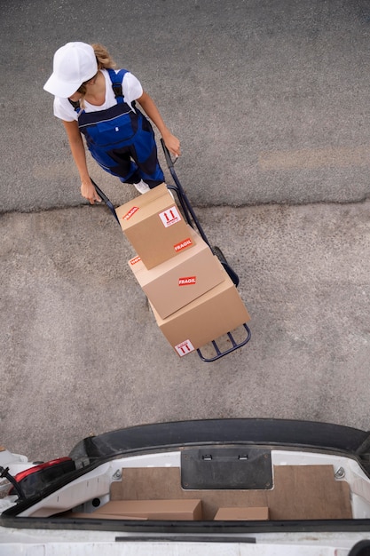 Delivery woman carrying boxes full shot