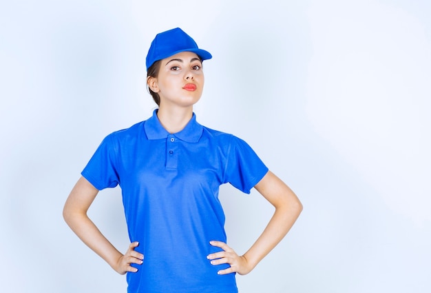 Delivery woman employee in uniform standing and posing with hands oh hips.