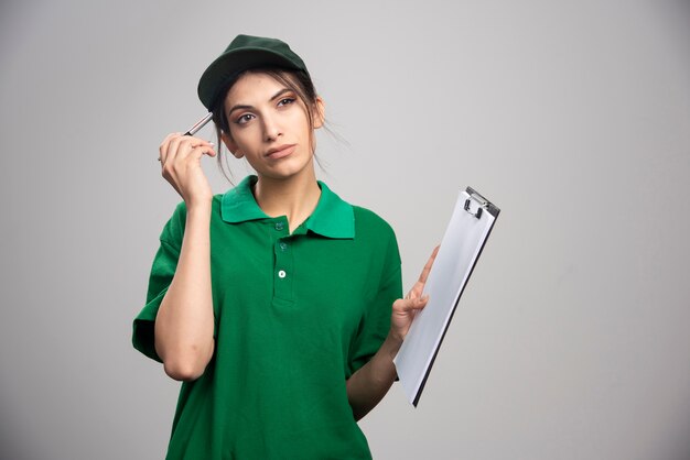 Delivery woman in green uniform holding clipboard. 