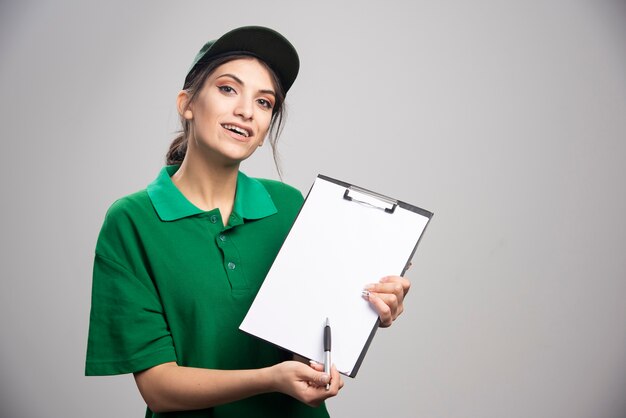 Delivery woman in green uniform shows where to sign. 