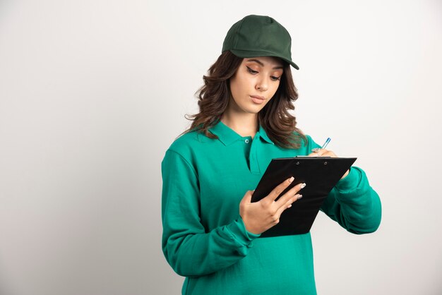 Delivery woman in green uniform writing order details.