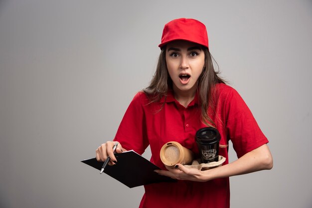 コーヒーカップとクリップボードを保持している配達の女性。