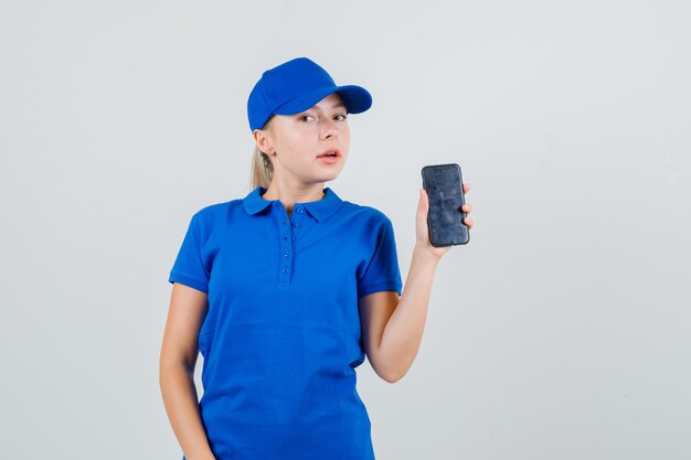 Delivery woman holding mobile phone in blue t-shirt and cap