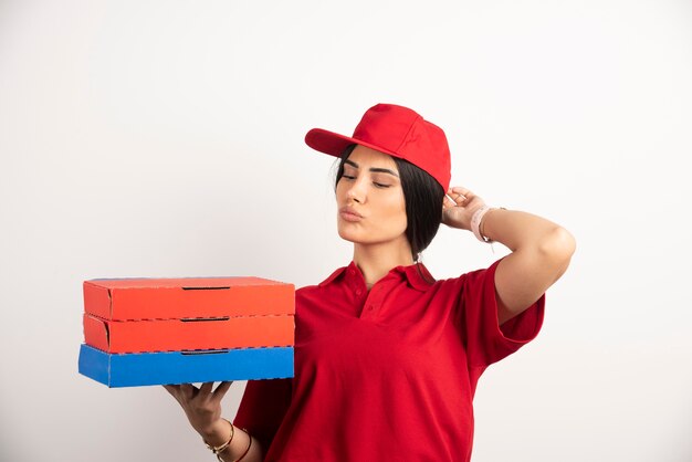 Delivery woman holding pizza boxes while inhaling the aroma. 