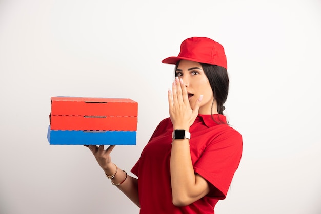 Free photo delivery woman holding pizza with shocked expression.