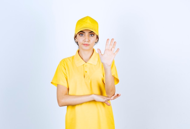 黄色い制服を着た出産の女性が立って、開いた手のひらを示しています。