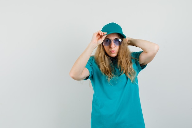 Free photo delivery woman looking at camera while adjusting cap in t-shirt, cap and looking cool