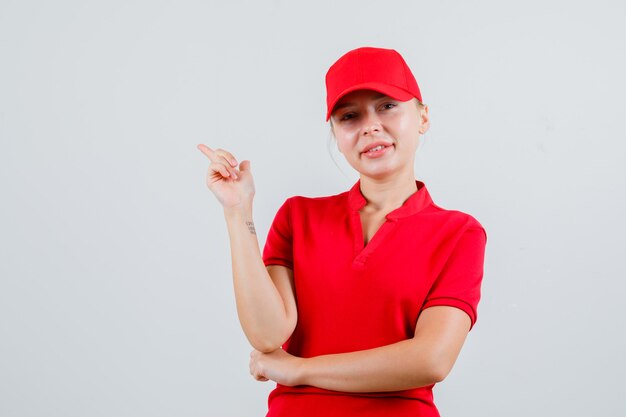 Доставщица показывает в красной футболке и кепке и выглядит веселой