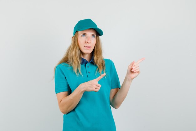 Delivery woman pointing away in t-shirt, cap and looking pensive 