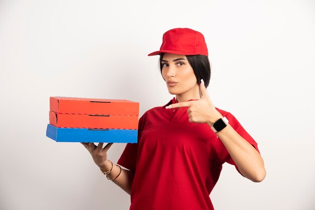 Delivery woman pointing at pizza boxes. 