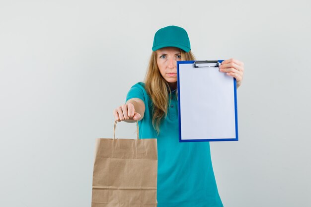 Delivery woman showing clipboard and paper bag in t-shirt, cap 