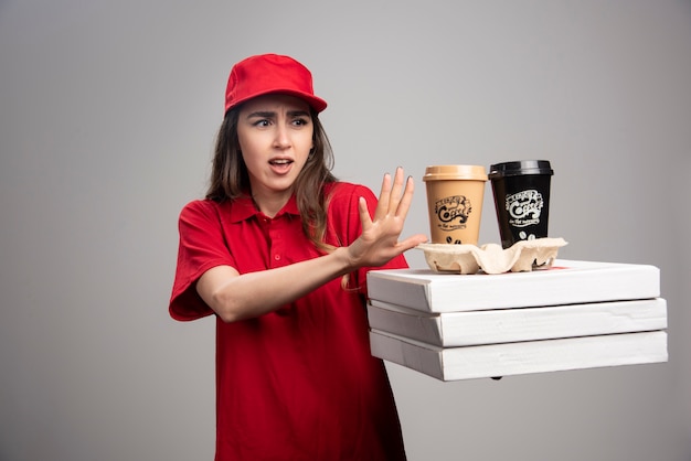 Free photo delivery woman standing away from pizza and coffee cups.