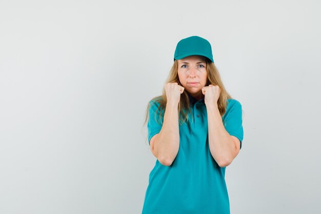 Delivery woman standing in fight pose in t-shirt, cap and looking powerful. 