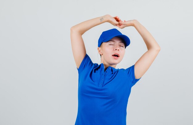 Delivery woman stretching arms in blue t-shirt and cap and looking relaxed