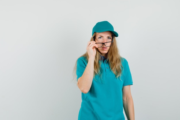 Женщина-доставщик снимает очки в футболке, кепке и выглядит сомнительно