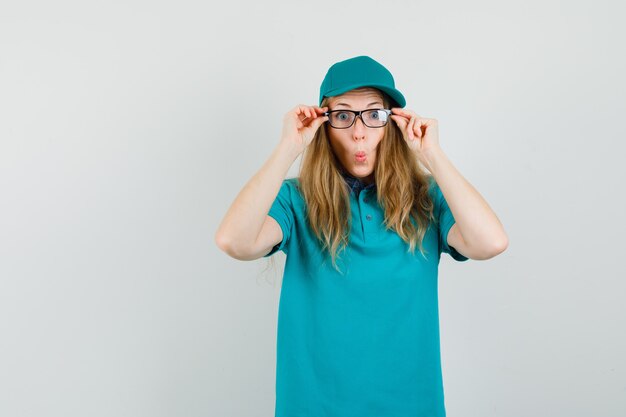 Delivery woman wearing glasses in t-shirt, cap and looking funny 