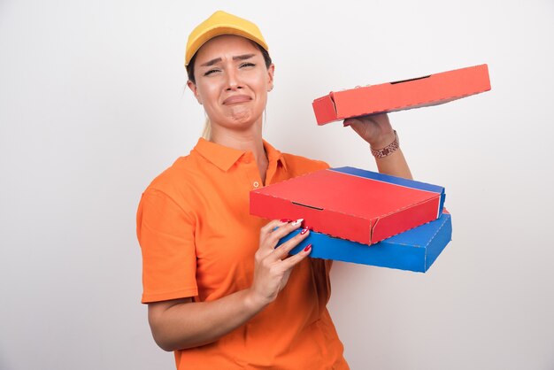 Delivery woman with bored expression holding pizza boxes.