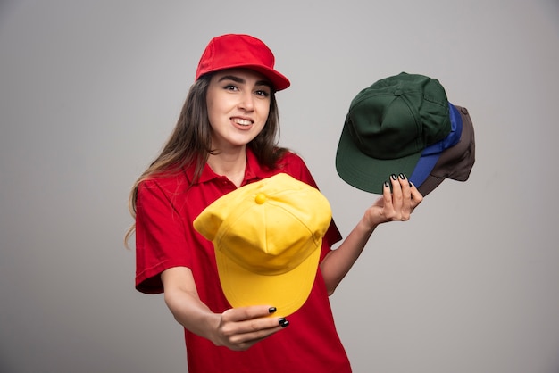 Delivery woman with colorful caps giving away one of them. 