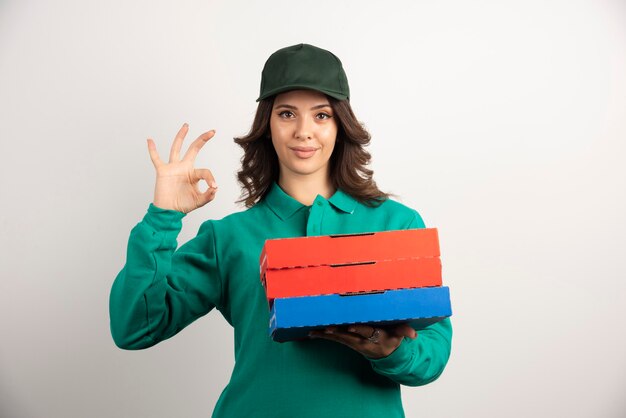 Delivery woman with pizza boxes standing on white.