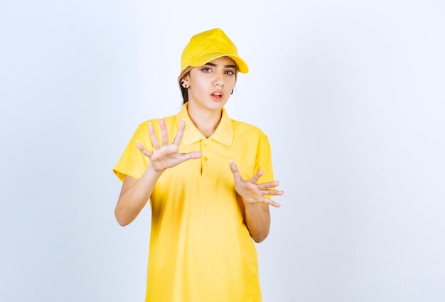 Delivery woman in yellow uniform standing and looking at camera.