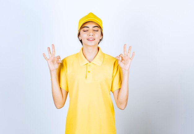 Delivery woman in yellow uniform standing and meditating .