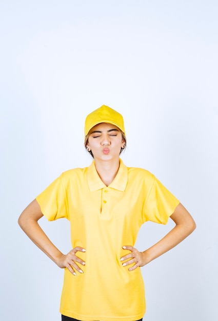 Delivery woman in yellow uniform standing and posing with hands on hips.