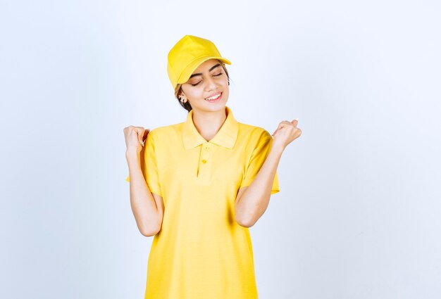 Delivery woman in yellow uniform standing and posing.