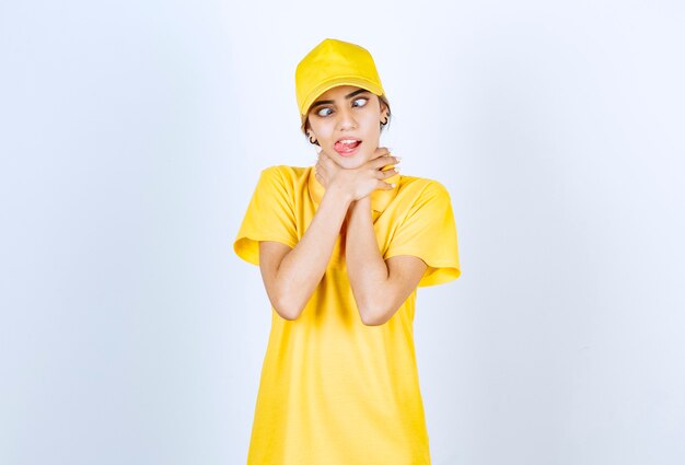 Delivery woman in yellow uniform standing and strangling herself