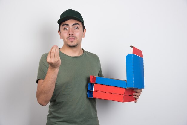 Deliveryman making hand sign and holding pizza boxes on white background.