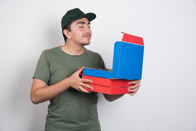 Deliveryman smelling pizza on white background.