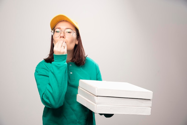 Deliverywoman carrying cardboards of pizza on a white. High quality photo