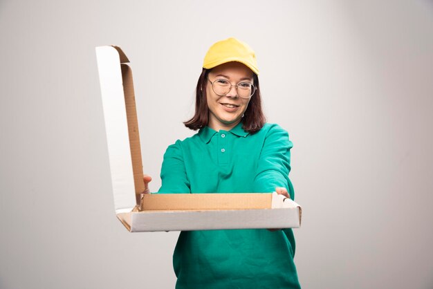 Deliverywoman giving a cardboard of pizza on a white. High quality photo