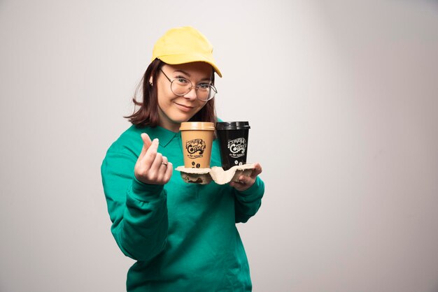 Deliverywoman holding cardboard of coffee cups on a white. High quality photo