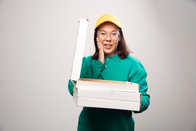 Deliverywoman holding cardboards of pizza on a white. High quality photo